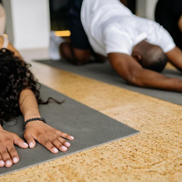 Person stretching on a yoga mat in a brightly lit, serene studio.