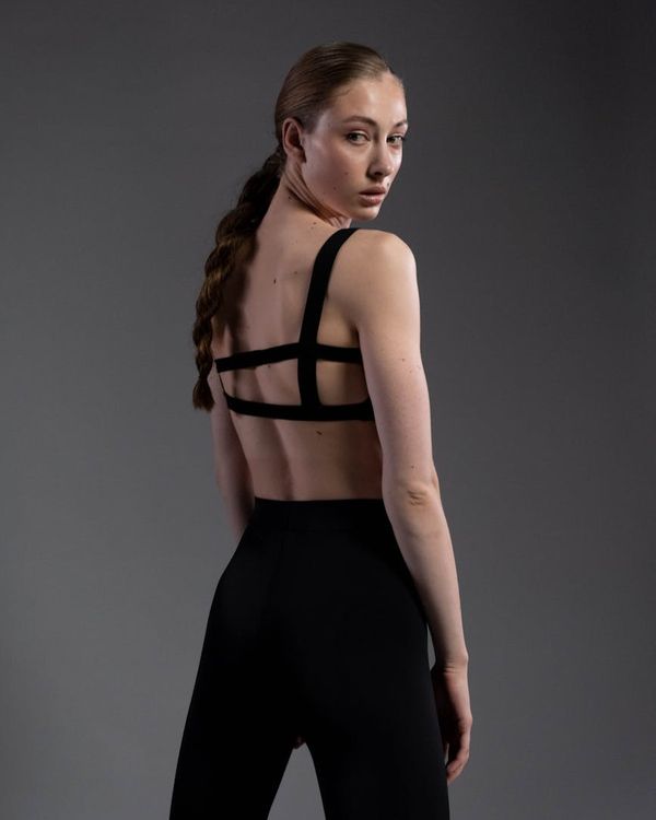 Woman in a graceful yoga pose against a dark, minimalist background.